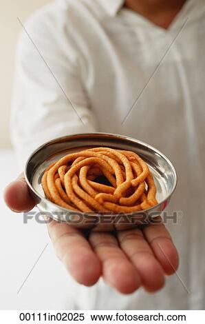 A man holds out a dish of muruku View Large Photo Image Stock Photography - A man holds out a dish of muruku. Fotosearch