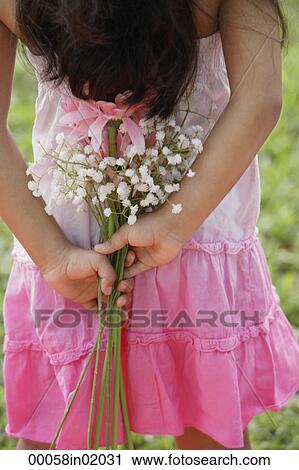 A small girl holds flowers behind her back View Large Photo Image Stock Image - A small girl holds flowers behind her back. Fotosearch
