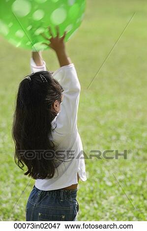 A small girl plays with a green ball View Large Photo Image Stock Photo - A small girl plays with a green ball. Fotosearch