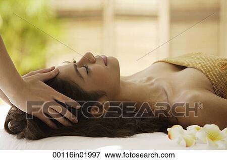 Stock Photo - A woman lying down with frangipani flowers around her. Fotosearch