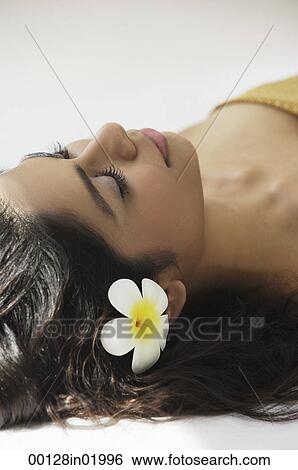A woman lying down with frangipani flowers around her View Large Photo Image Stock Photograph - A woman lying down with frangipani flowers around her. Fotosearch