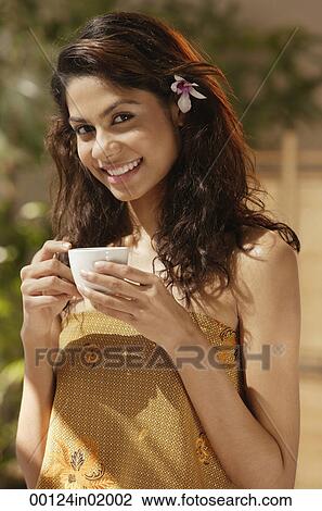 A woman with a flower in her hair drinks a cup of tea View Large Photo Image Stock Image - A woman with a flower in her hair drinks a cup of tea. Fotosearch