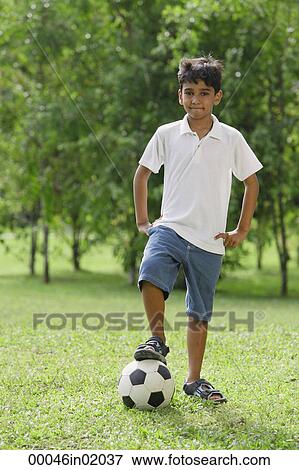 A young boy looks at the camera as he rests his foot on a soccerball View Large Photo Image Stock Photo - A young boy looks at the camera as he rests his foot on a soccerball. Fotosearch