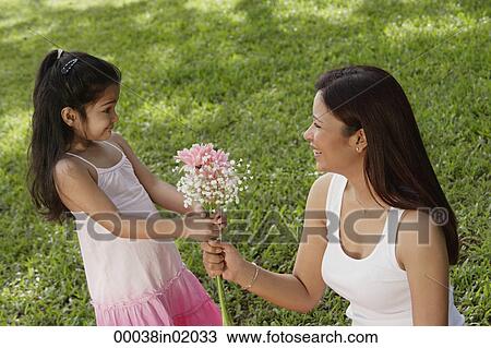 A young girl gives her mother a bunch of flowers View Large Photo Image Stock Image - A young girl gives her mother a bunch of flowers. Fotosearch