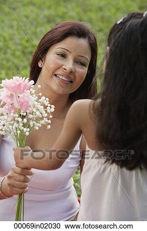 A young girl gives her mother a bunch of flowers View Large Photo Image Stock Image - A young girl gives her mother a bunch of flowers. Fotosearch