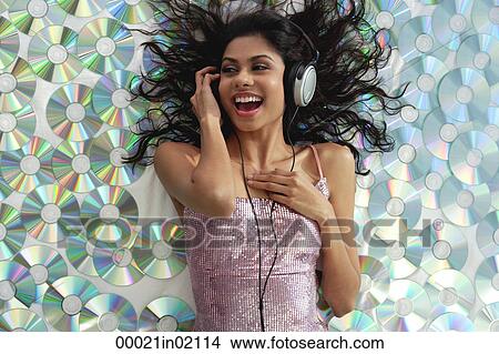 A young woman listens to music as she lies down on CDs View Large Photo Image Picture - A young woman listens to music as she lies down on CDs. Fotosearch