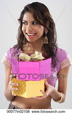A young woman smiles as she holds gifts View Large Photo Image Stock Photo - A young woman smiles as she holds gifts. Fotosearch