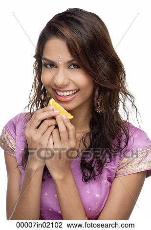 A young woman smiles at the camera as she eats a slice of orange View Large Photo Image Stock Image - A young woman smiles at the camera as she eats a slice of orange. Fotosearch