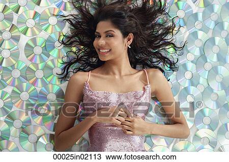 A young woman smiles at the camera as she lies down on CDs View Large Photo Image Stock Image - A young woman smiles at the camera as she lies down on CDs. Fotosearch