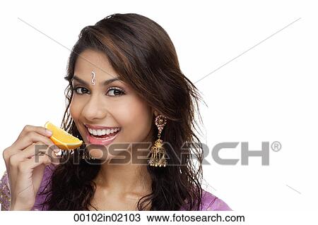 A young woman smiles at the camera as she eats a slice of orange View Large Photo Image Stock Image - A young woman smiles at the camera as she eats a slice of orange. Fotosearch