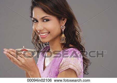 A young woman smiles at the camera as she holds a candle View Large Photo Image Stock Photograph - A young woman smiles at the camera as she holds a candle. Fotosearch