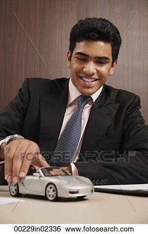 Stock Photograph - Businessman playing with toy car. Fotosearch