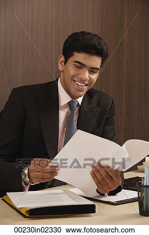 Businessman reading paper and smiling View Large Photo Image Stock Image - Businessman reading paper and smiling. Fotosearch