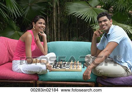 Couple playing chess outdoors, smiling at camera View Large Photo Image Picture - Couple playing chess outdoors, smiling at camera. Fotosearch