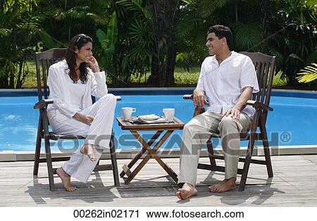 Couple sitting by the pool, looking at each other View Large Photo Image Stock Image - Couple sitting by the pool, looking at each other. Fotosearch