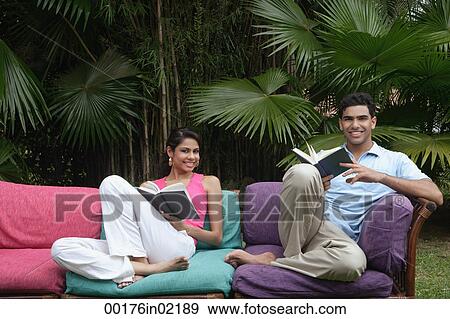 Couple sitting on sofa outdoors, smiling at camera View Large Photo Image Stock Photo - Couple sitting on sofa outdoors, smiling at camera. Fotosearch