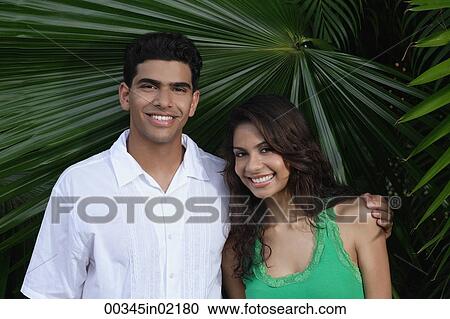 Couple with arms around each other, smiling at camera View Large Photo Image Stock Image - Couple with arms around each other, smiling at camera. Fotosearch