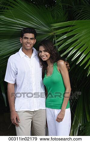 Couple with arms around each other, smiling at camera View Large Photo Image Stock Photo - Couple with arms around each other, smiling at camera. Fotosearch
