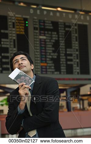 Man holding passport on his chin in the airport View Large Photo Image Stock Photo - Man holding passport on his chin in the airport. Fotosearch