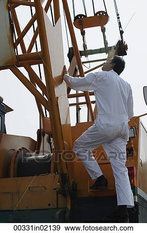 Stock Photo - Man in work uniform getting onto crane. Fotosearch