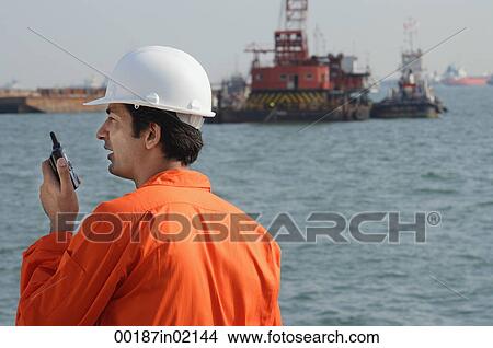 Man in work uniform talking into walkie talkie View Large Photo Image Picture - Man in work uniform talking into walkie talkie. Fotosearch