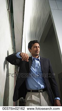 Stock Image - Man leaning against wall. Fotosearch