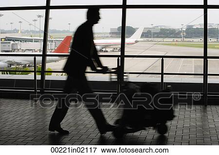 Man pushing trolley at airport View Large Photo Image Stock Photo - Man pushing trolley at airport. Fotosearch