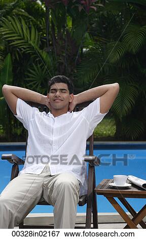 Man relaxing in chair by the pool View Large Photo Image Stock Photo - Man relaxing in chair by the pool. Fotosearch