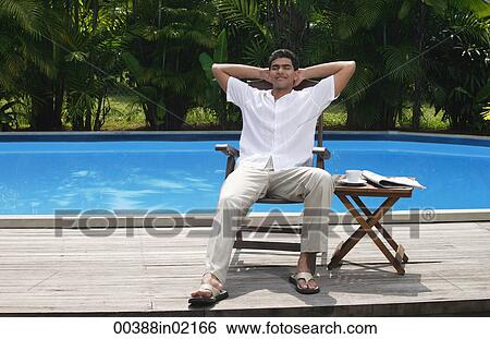 Man relaxing in chair by the pool View Large Photo Image Stock Photograph - Man relaxing in chair by the pool. Fotosearch