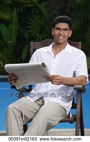 Man sitting in chair holding a newspaper and looking at camera View Large Photo Image Stock Image - Man sitting in chair holding a newspaper and looking at camera. Fotosearch