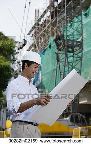 Man smiling while looking at plans View Large Photo Image Stock Photo - Man smiling while looking at plans. Fotosearch
