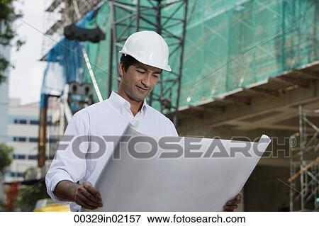 Man with helmet, looking at plans View Large Photo Image Stock Photo - Man with helmet, looking at plans. Fotosearch