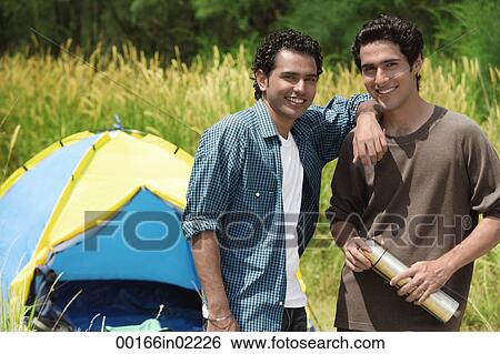 Stock Photograph - Two friends camping smiling at camera. Fotosearch