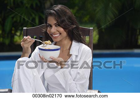 Woman in chair by the pool, holding bowl of cereal and looking at camera View Large Photo Image Stock Image - Woman in chair by the pool, holding bowl of cereal and looking at camera. Fotosearch