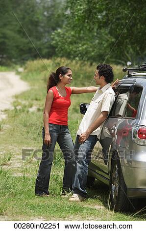 Young couple by car looking at each other View Large Photo Image Stock Image - Young couple by car looking at each other. Fotosearch