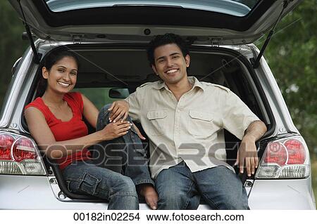Young couple sitting in car boot smiling at camera View Large Photo Image Picture - Young couple sitting in car boot smiling at camera. Fotosearch