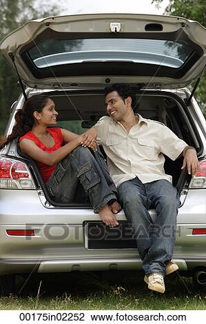 Young couple sitting in car boot View Large Photo Image Stock Image - Young couple sitting in car boot. Fotosearch