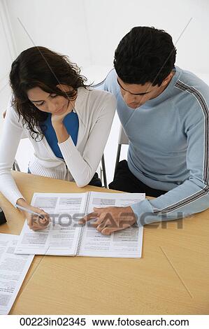 Stock Photography - Young couple studying paper. Fotosearch