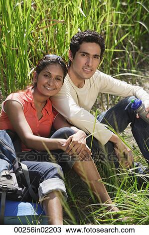 Stock Image - Young couple taking a break, smiling at camera. Fotosearch