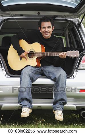 Young man sitting car boot playing guitar View Large Photo Image Stock Photography - Young man sitting car boot playing guitar. Fotosearch