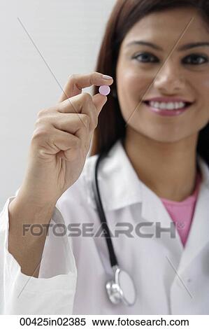 Stock Photography - Doctor holding up a pill. Fotosearch
