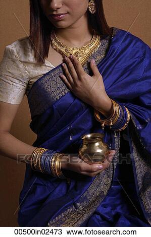 Stock Image - Indian woman wearing sari and holding offering. Fotosearch