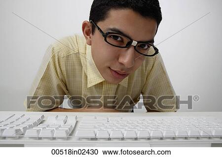 Stock Image - Nerd looking over keyboard. Fotosearch