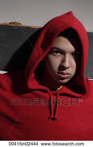 young man wearing red hooded sweatshirt holding skateboard View Large Photo Image Picture - young man wearing red hooded sweatshirt holding skateboard. Fotosearch