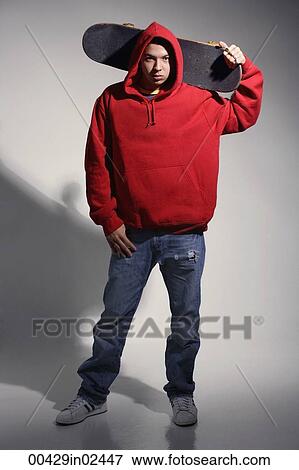 Stock Photo - young man wearing red hooded sweatshirt holding skateboard. Fotosearch