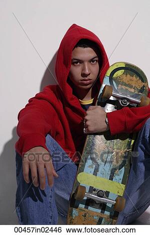 Stock Photograph - young man wearing red hooded sweatshirt holding skateboard. Fotosearch