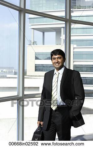 Stock Image - business man holding briefcase, smiling. Fotosearch