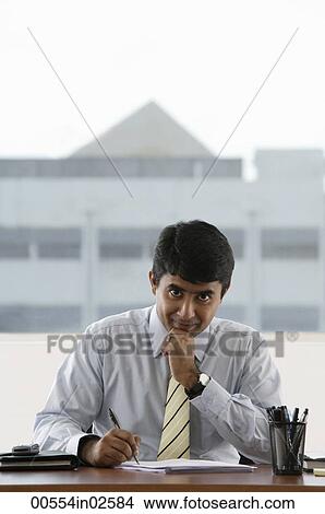 Picture - business man writing at his desk. Fotosearch