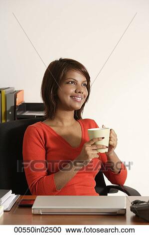 Stock Image - Business woman holding coffee mug, smiling. Fotosearch