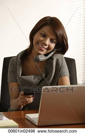 Business woman talking on the phone, looking at laptop and mobile device. View Large Photo Image Stock Photo - Business woman talking on the phone, looking at laptop and mobile device.. Fotosearch